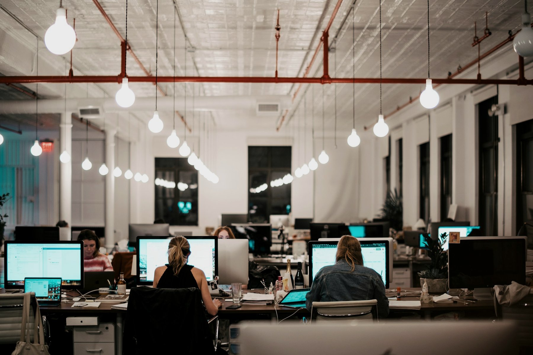 An open office with people working under pendant lights